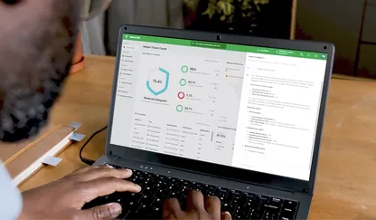 Video still shot over a person's shoulder as they type on a laptop showing a governance dashboard with a circular chart and status indicators.